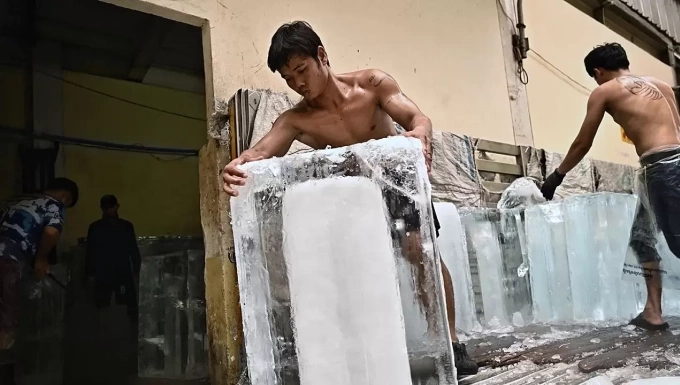 Công nhân chuyển khối đá lạnh vào kho chứa trong khu chợ đồ tươi sống ở Bangkok năm 2023. Ảnh: AFP