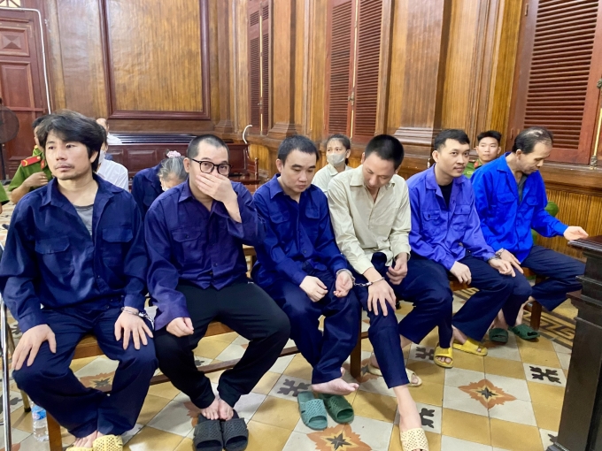 Bị cáo Nguyễn Lập Sơn (thứ 3 từ trái qua phải) và vợ là Phan Thị Bích Trâm (ngồi trong cùng hàng dưới) cùng các bị cáo tại tòa. Ảnh: Hải Duyên