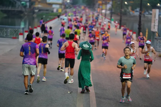 Runner với trang phục áo dài, nón lá in logo Huda chạy trên Đập Đá. Ảnh: VnExpress Marathon