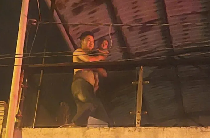 Đại úy Kiệt bế bé 13 tháng tuổi mắc kẹt trong nhà cháy ra ban công để đưa ra ngoài an toàn. Ảnh: Công an cung cấp